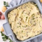 mashed potato casserole topped with parsley in a blue square casserole dish.