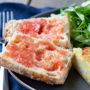 pan con tomate on a gray plate with a fork nearby