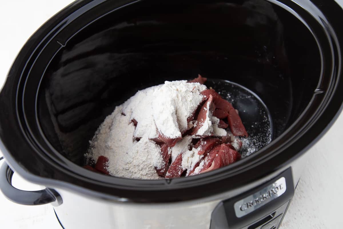steak strips and flour in a slow cooker.