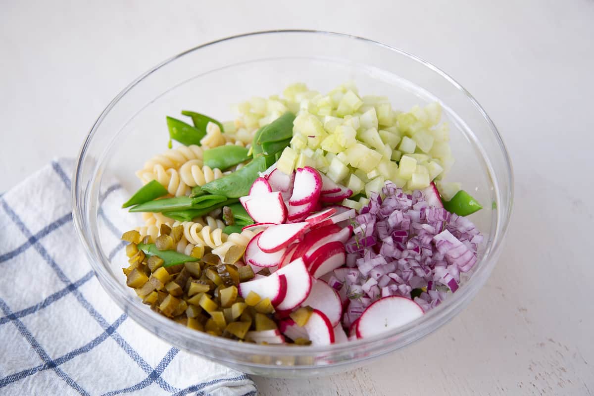 glass bowl filled with tuna pasta salad ingredients.