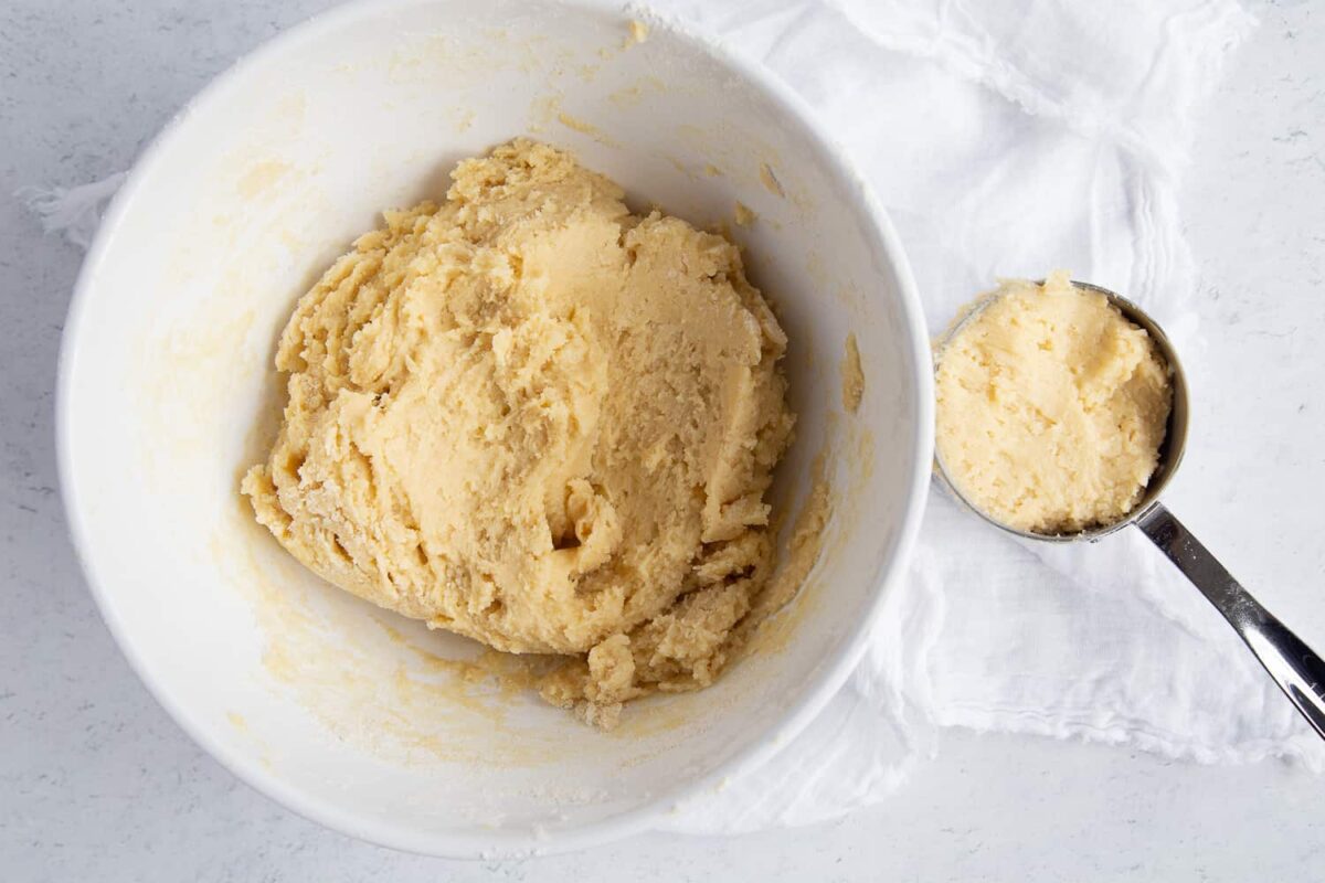 coffee cake dough in a white bowl alongside a 1-cup measuring cup of dough.