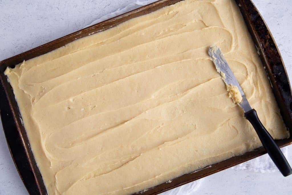 dough spread into a pan with an offset spatula sitting on top.