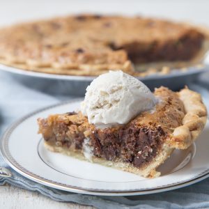 slice of cookie pie topped with ice cream with an entire cookie pie behind it.
