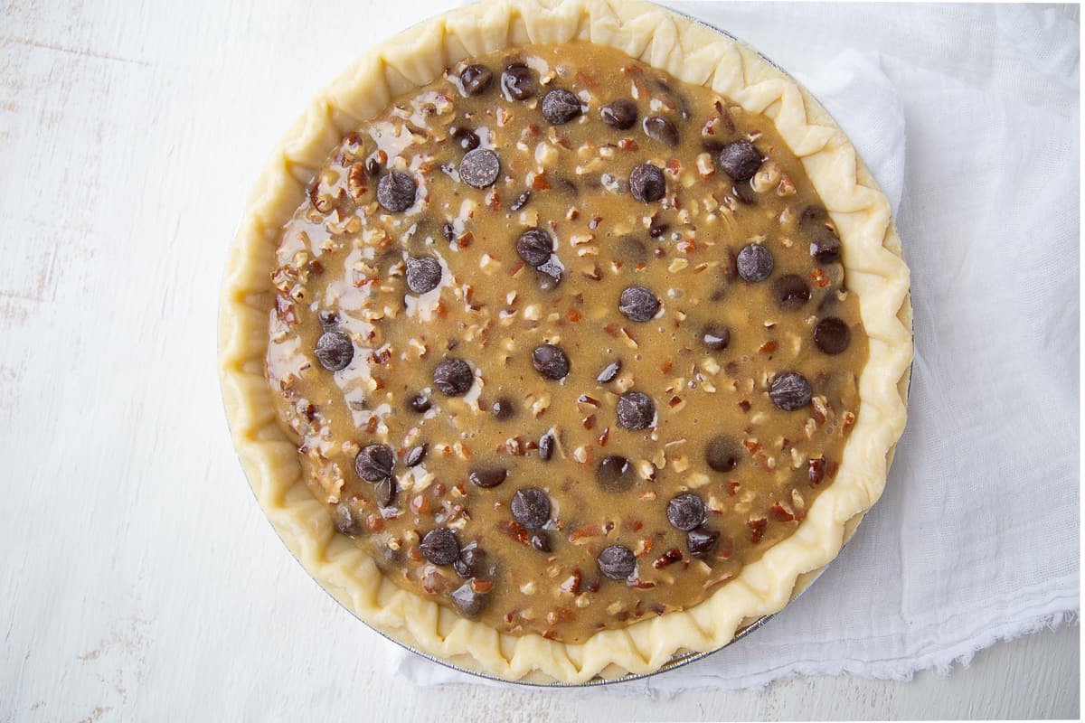 chocolate chip cookie pie batter in an unbaked pie shell. 
