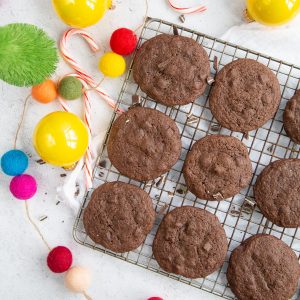 chocolate cookies on a wire rack with colorful ball garland and yellow christmas balls.