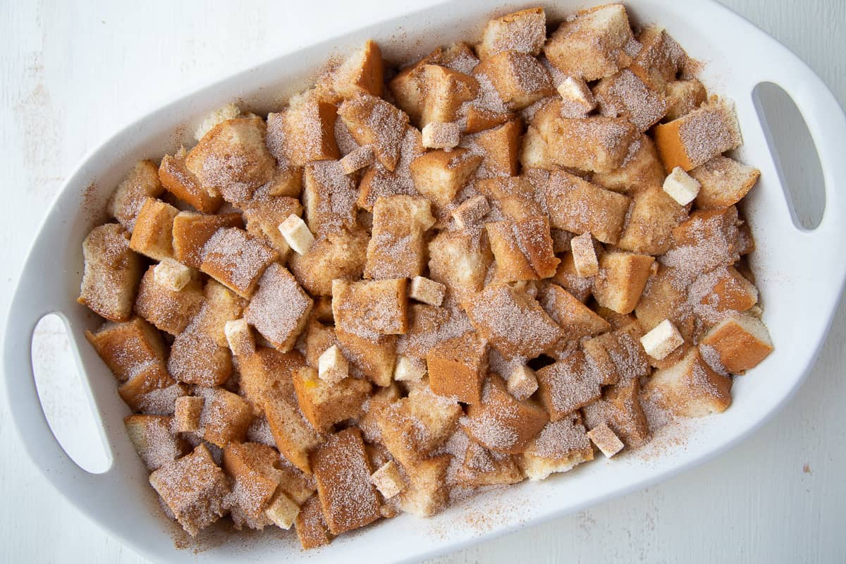 french toast casserole topped with mini cubes of butter and cinnamon sugar.