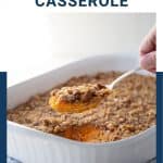 hand lifting spoon of sweet potato casserole out of white casserole dish.