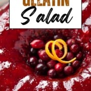 ring of cranberry gelatin salad with cranberries and orange peel in the center.