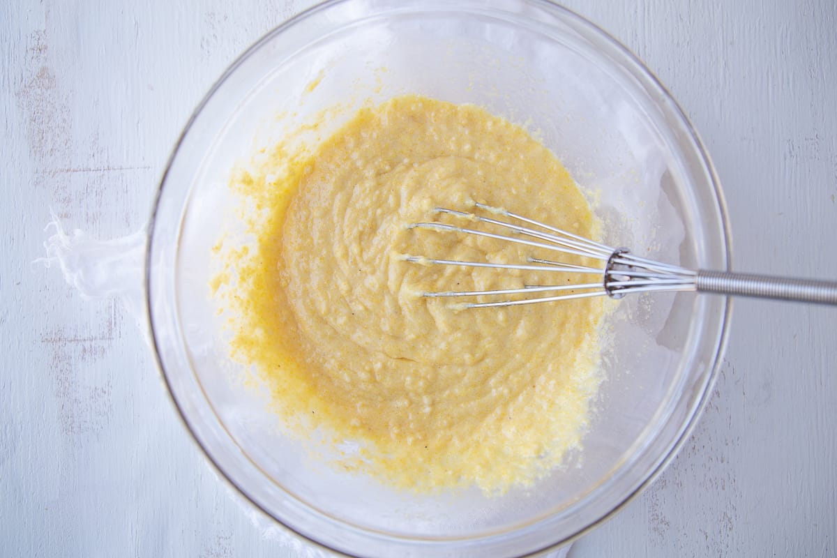 corn muffin mix, eggs, and butter whisked together in a glass bowl.