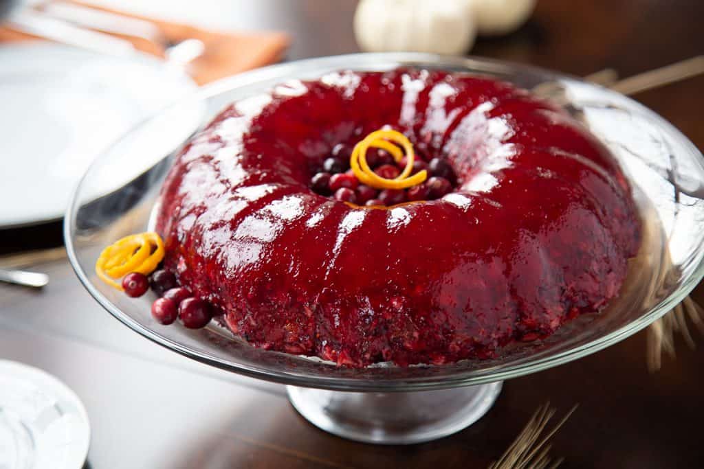 cranberry jello ring on a glass cake stand.