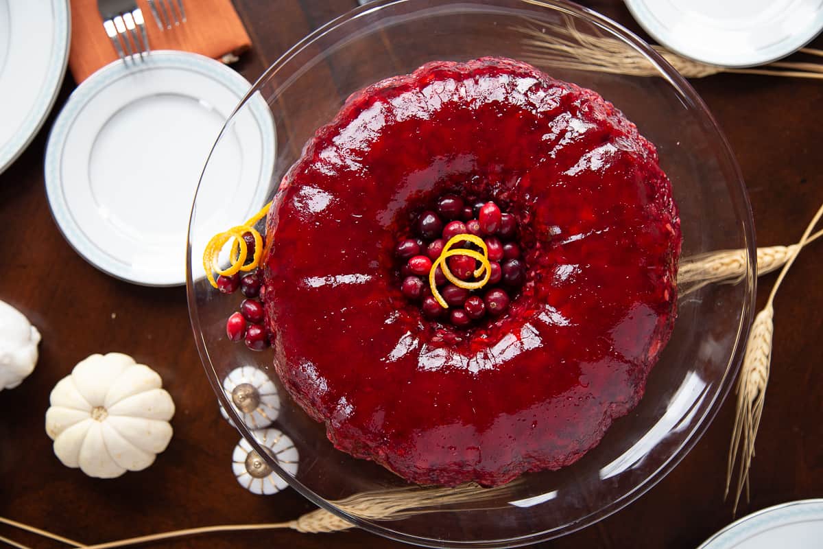 cranberry jello salad on a wooden table with white pumpkins and wheat stalks.