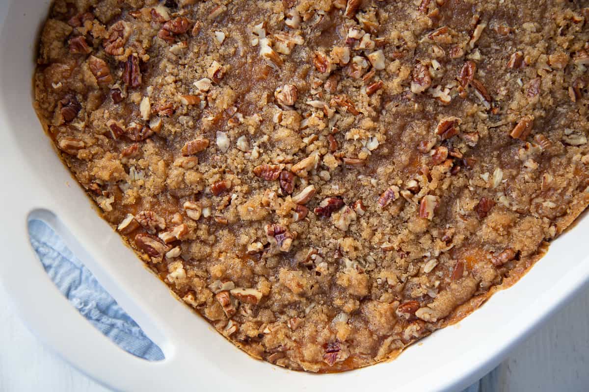 sweet potato casserole topped with pecans in a white casserole dish.