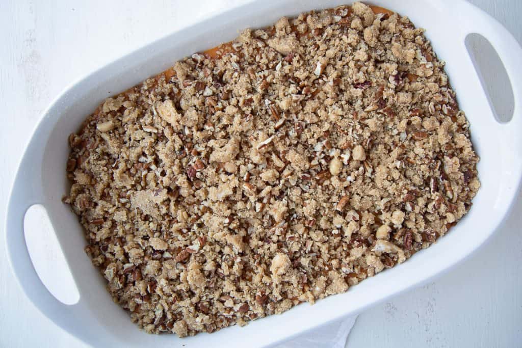 unbaked pecan mixture over sweet potatoes in a casserole dish.