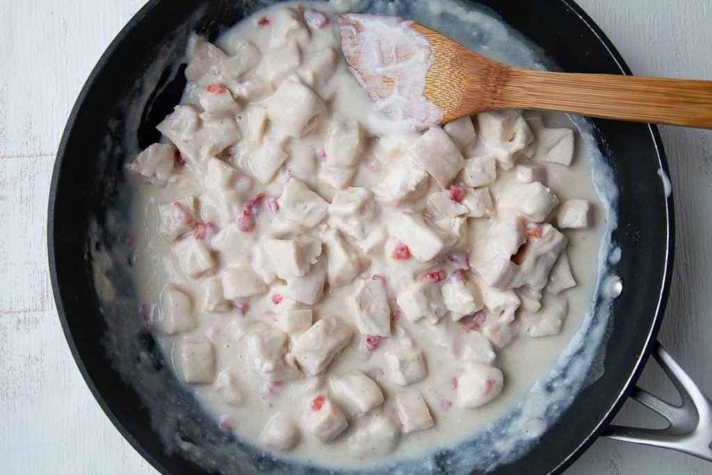 creamy turkey a la king in a nonstick skillet with a wooden spoon.