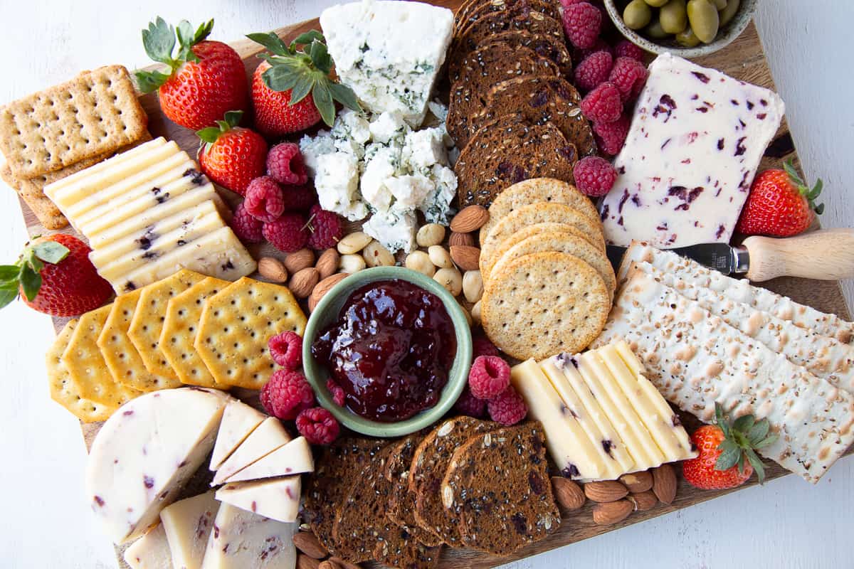 full and bountiful cheese board with a variety of cheese and crackers and fruit.