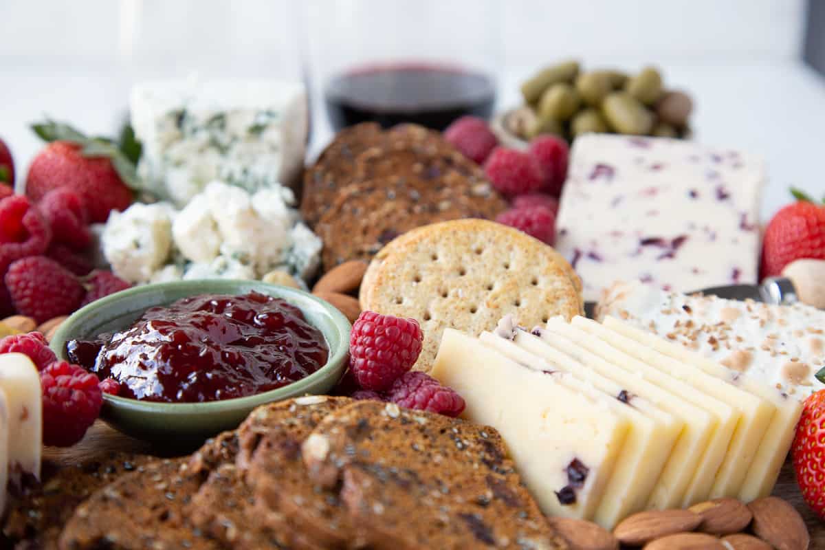 jam, olives, and cheese on a wooden board.