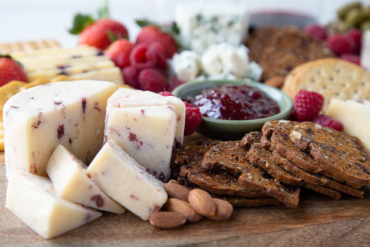 cranberry cheddar, almonds, and artisan crisp crackers on a wooden board.