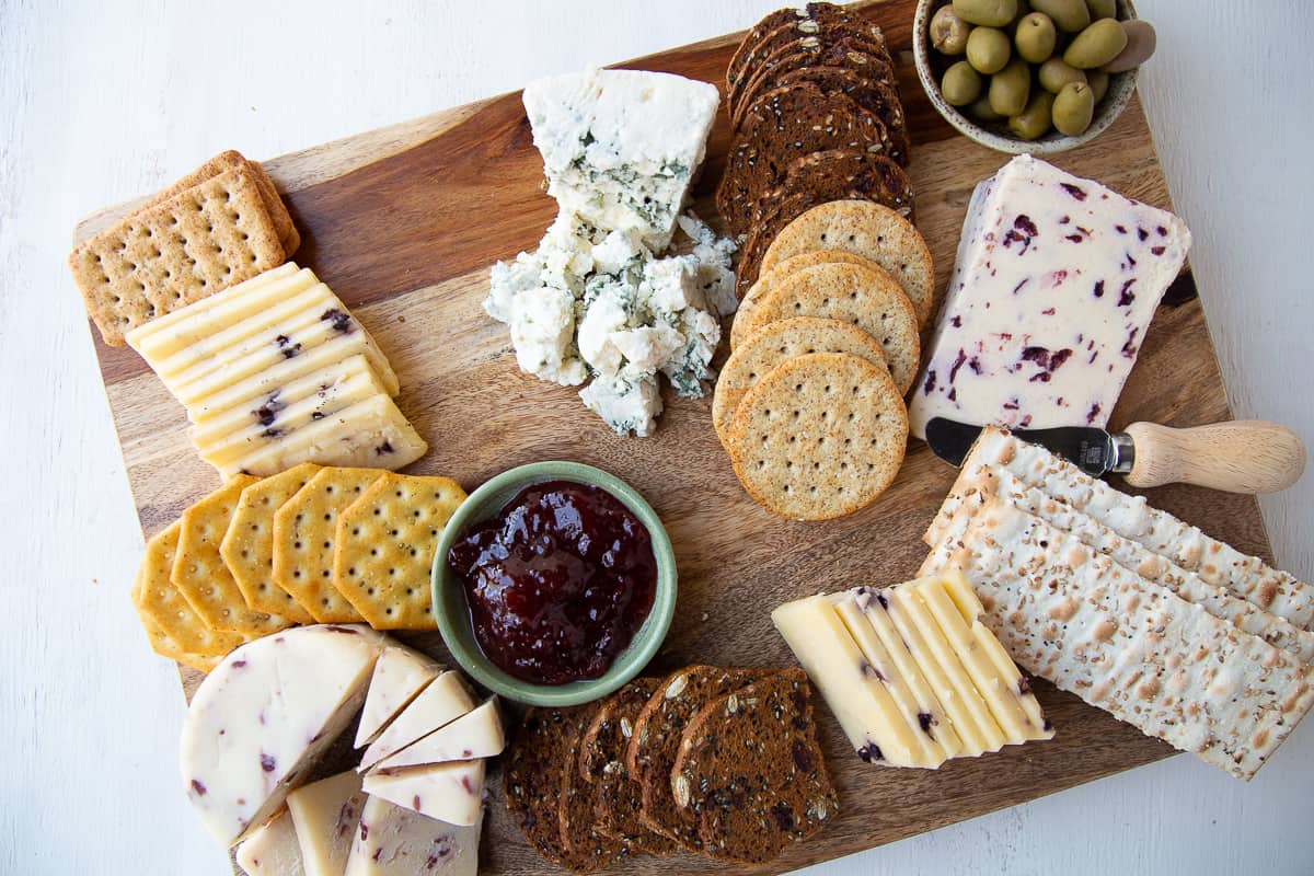 crackers, cheese, and olives on a wooden board.