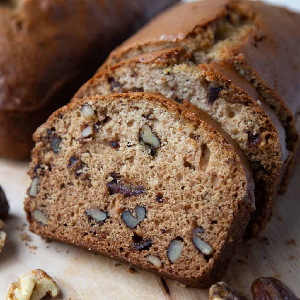 slice of date nut bread next to a whole loaf.