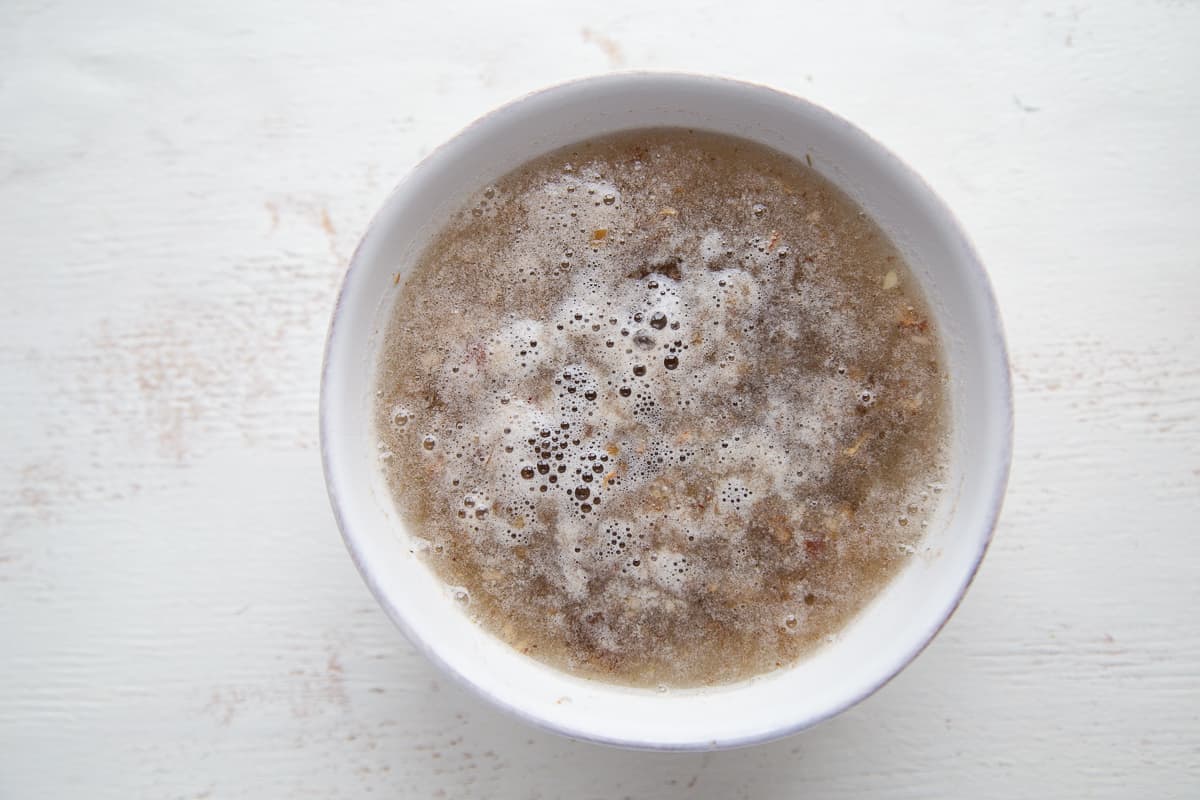 dates soaking in water in a white bowl.