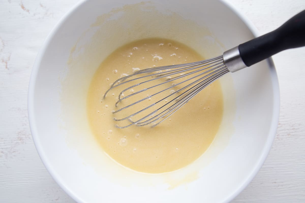egg and sugar mixture with a whisk in a white bowl.