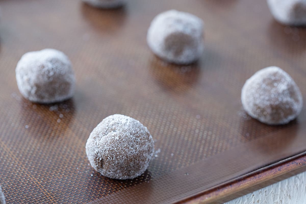 uncooked ginger cookies on a baking sheet.