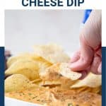 hand scooping nacho cheese dip from a white bowl.