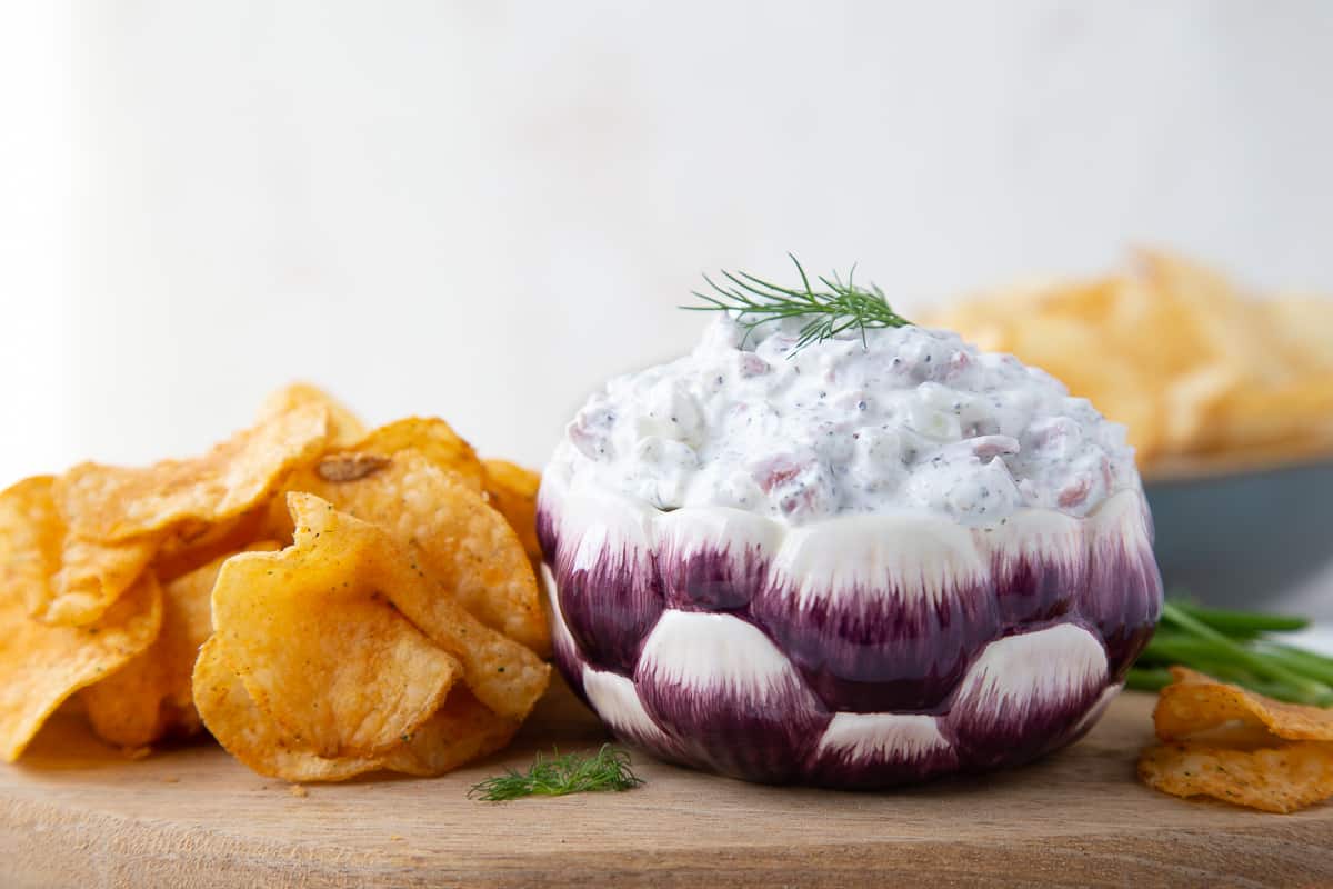 beef chip dip in a purple and white bowl, sitting on a wooden tray with chips beside it.