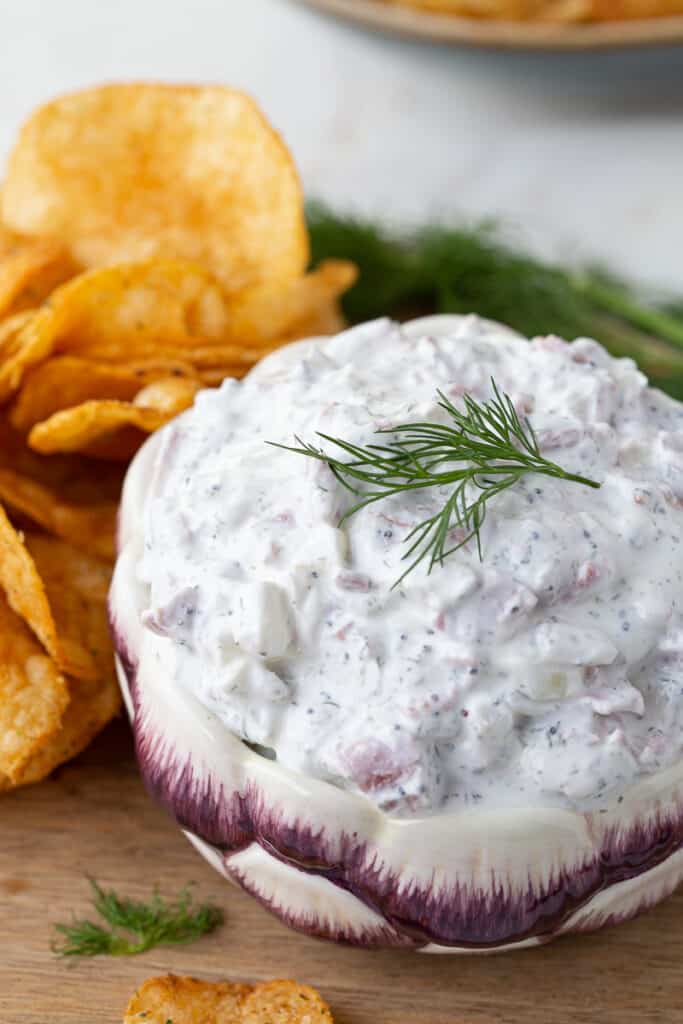 beef chip dip in a purple and white bowl, with potato chips on the side.