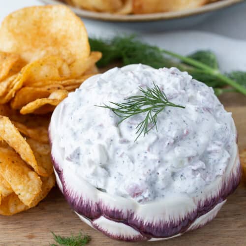 beef chip dip in a purple and white bowl, surrounded by potato chips.
