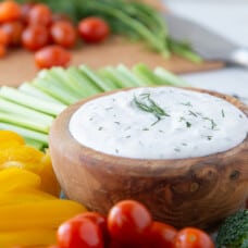wooden bowl of dill dip surrounded by raw veggies.