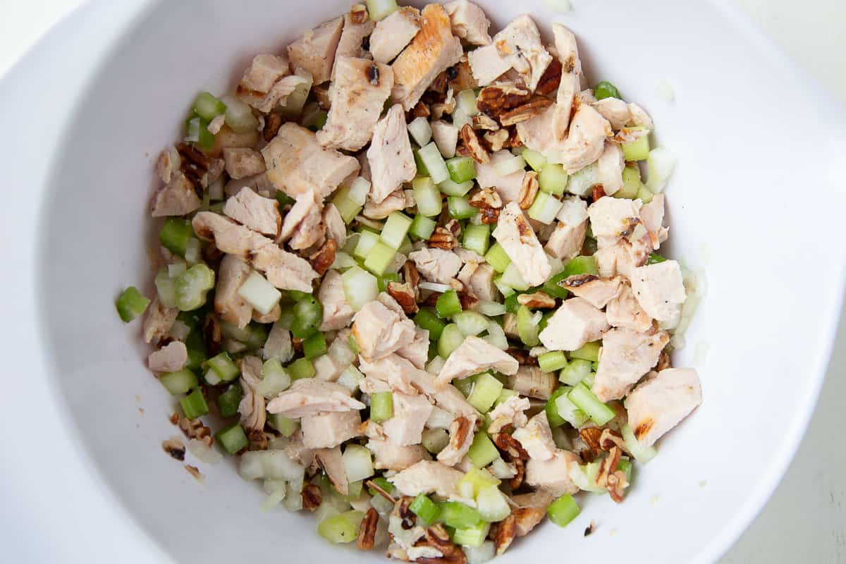 chicken, celery, and pecans in a large white bowl.