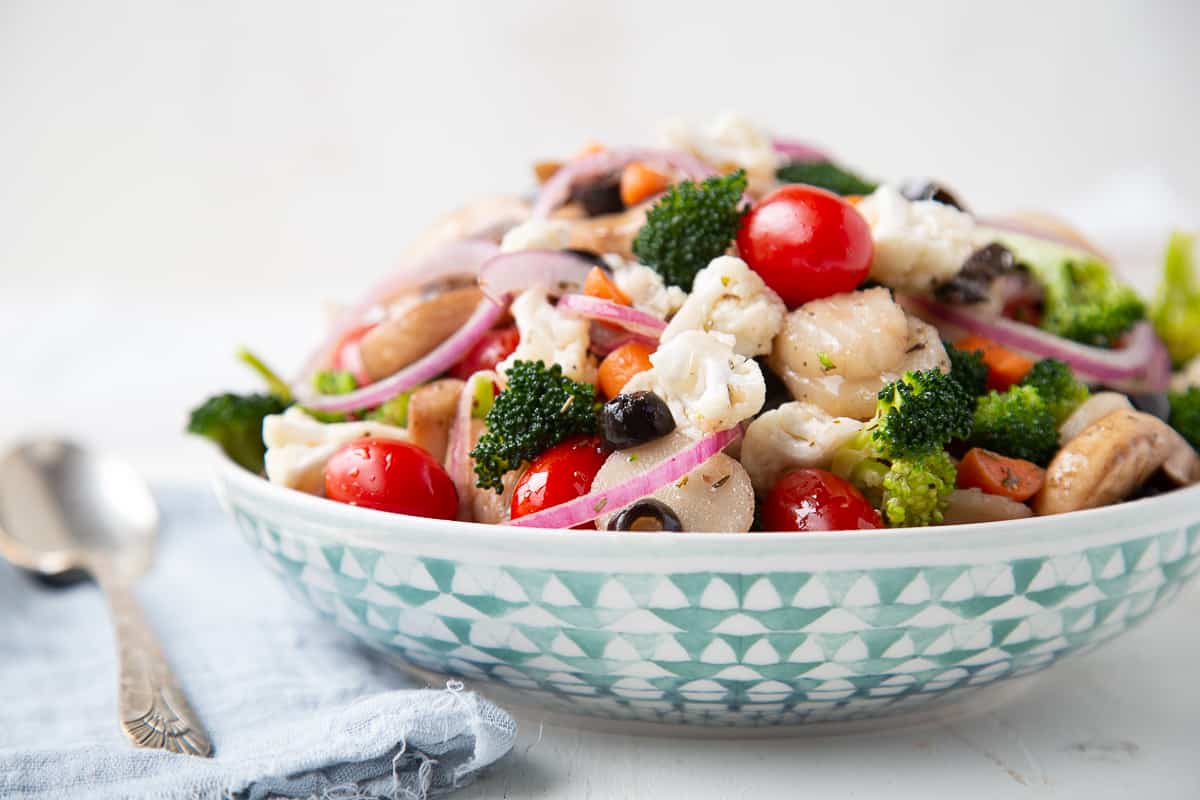 low bowl with a green design with marinated veggie salad inside.