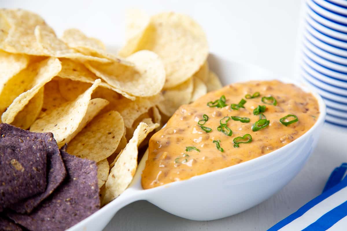 nacho cheese dip in a chips & dip platter, topped with sliced green onions.