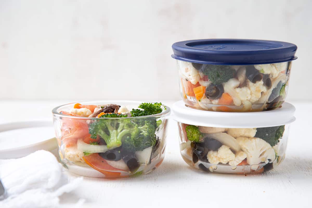 small glass bowls with lids filled with veggie salad.