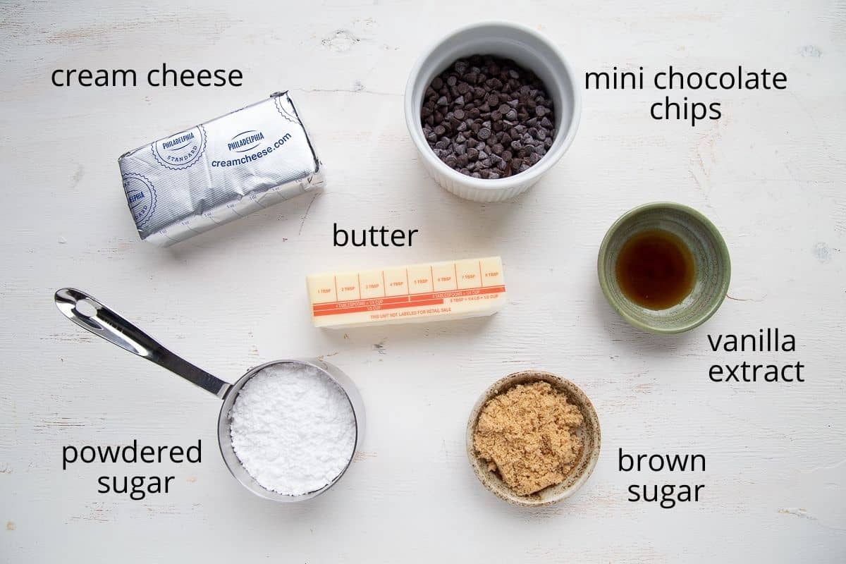 cream cheese, butter, chocolate chips, and other ingredients on a white table.