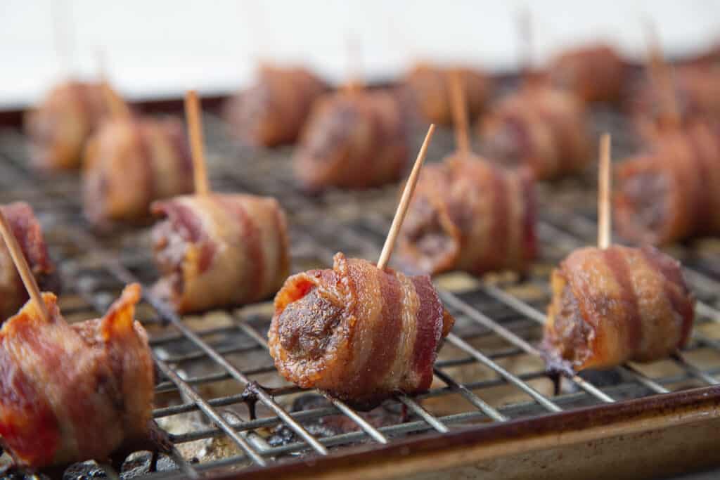 bacon wrapped meatballs with toothpicks on a wire rack.