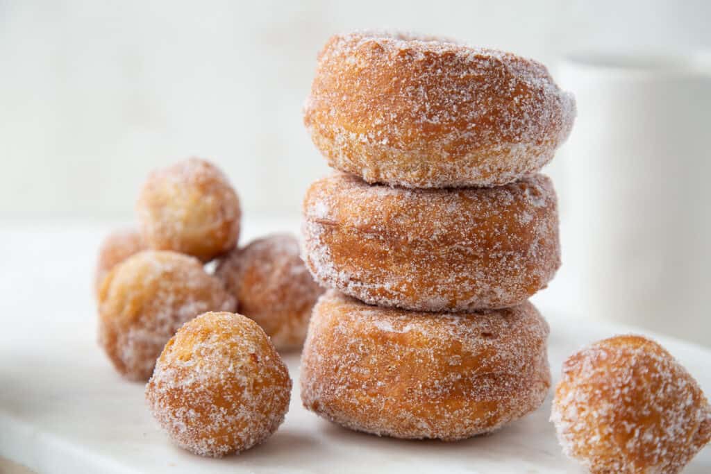 three biscuit donuts stacked up, surrounded by donut holes.