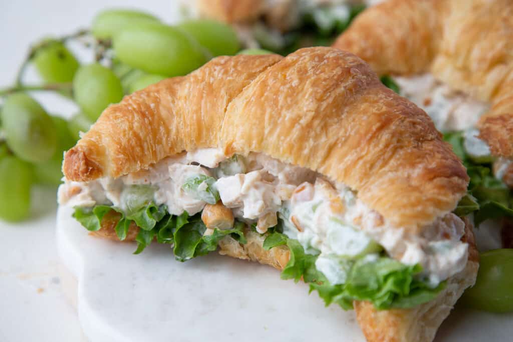chicken salad on a croissant with green leaf lettuce.