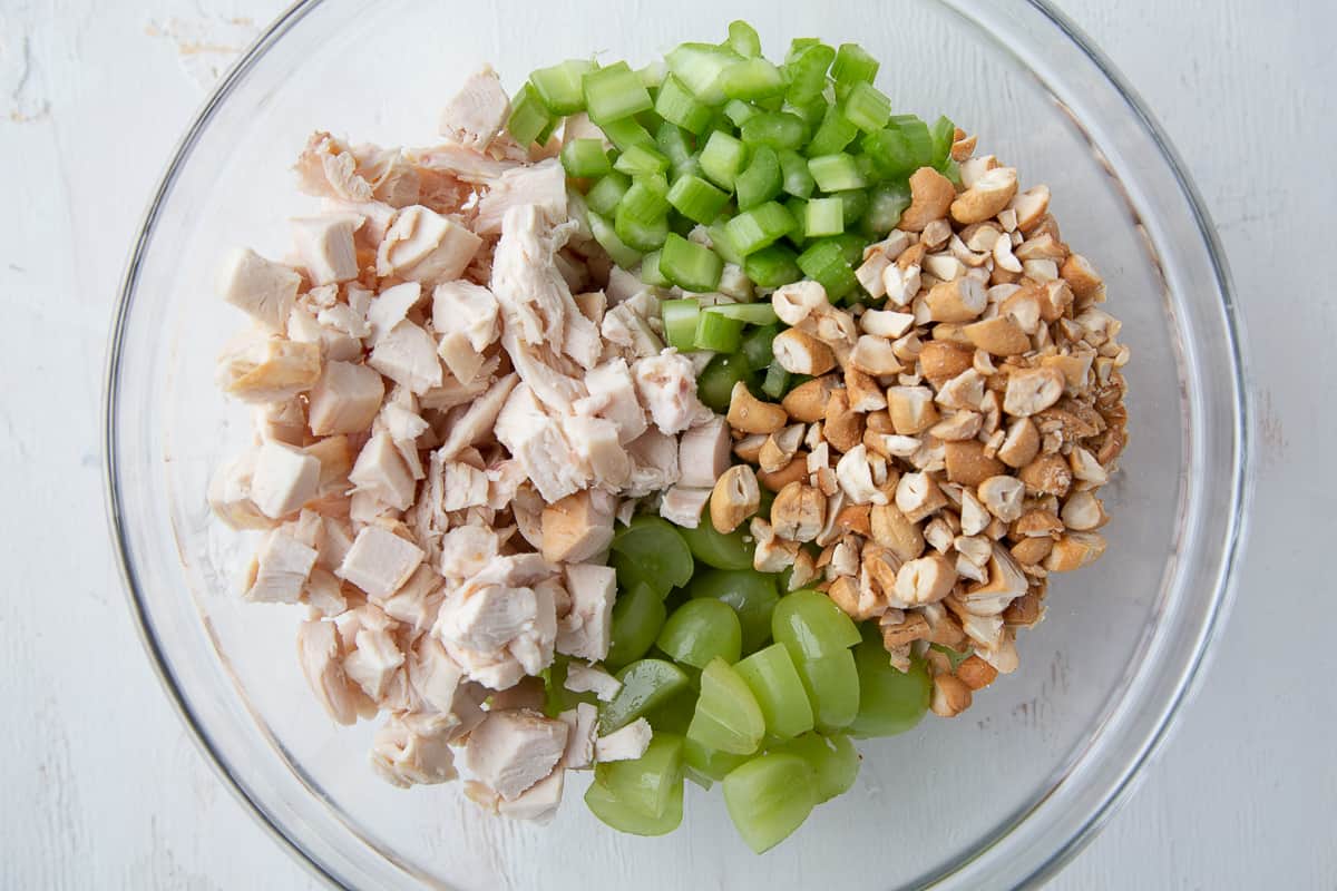 ingredients for chicken salad in a large glass bowl.