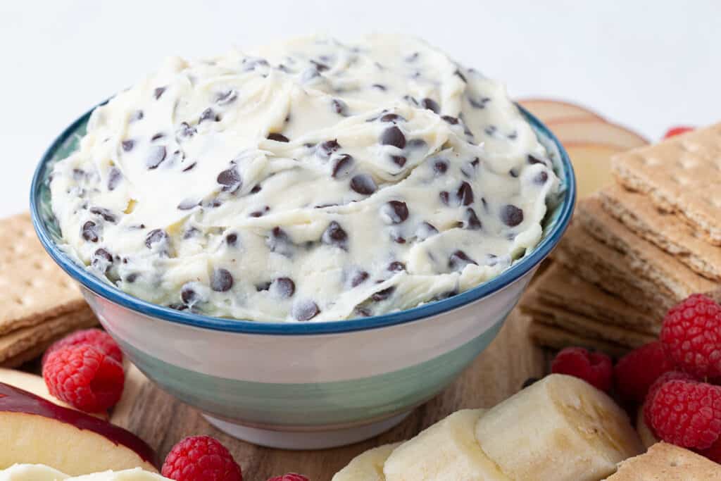 bowl of fluffy chocolate chip dip surrounded by graham crackers and fruit.