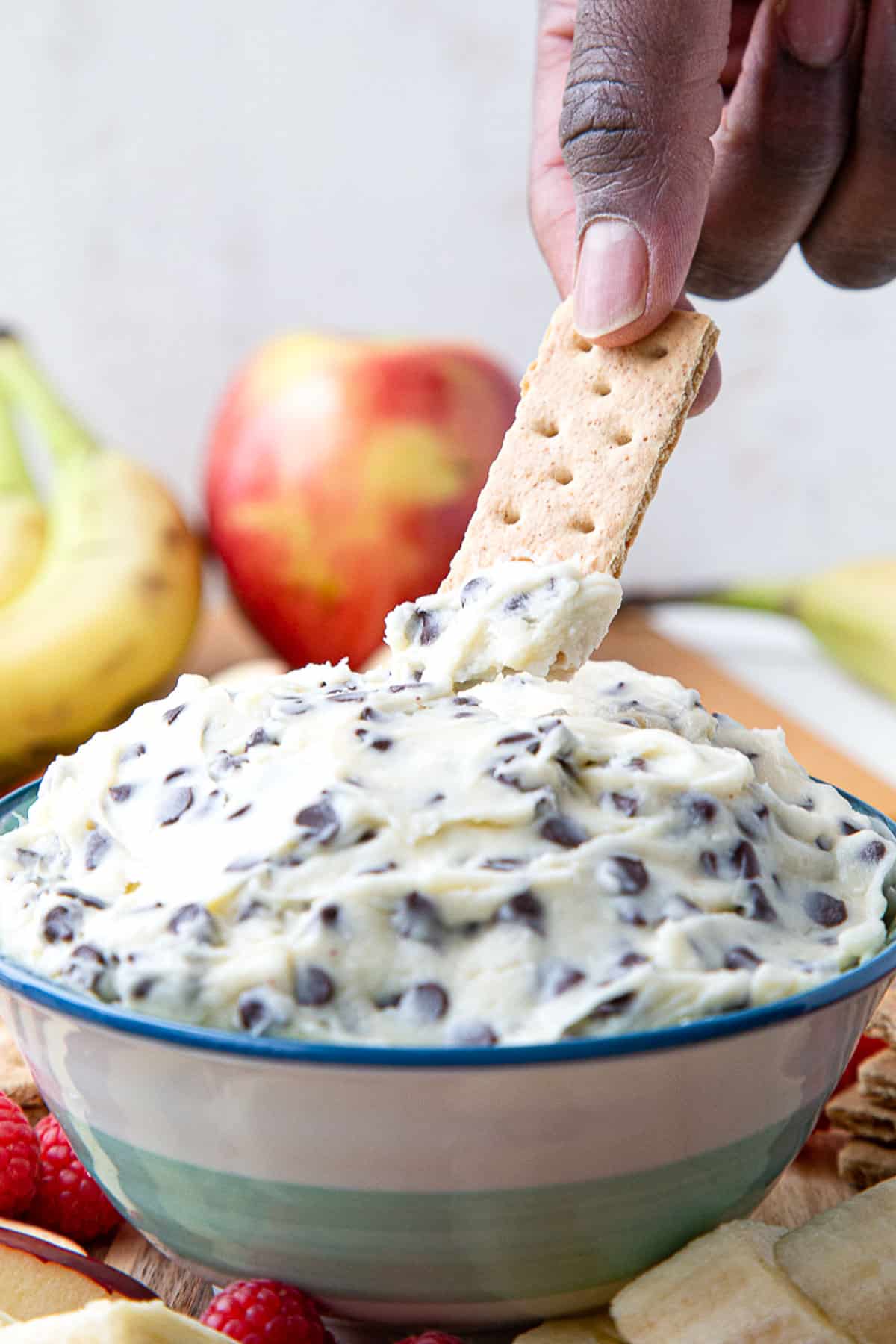 hand with a graham cracker scooping up chocolate chip dip.