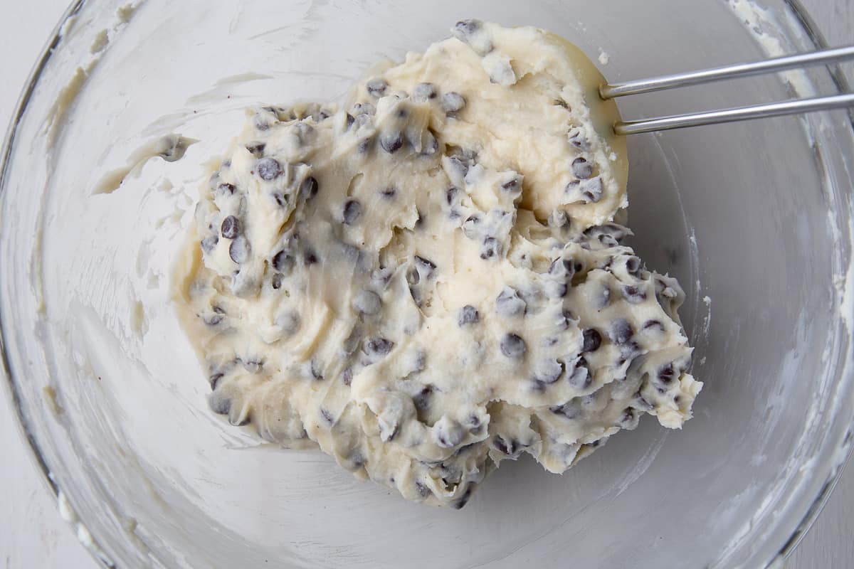 spatula stirring chocolate chips into a cream cheese mixture.
