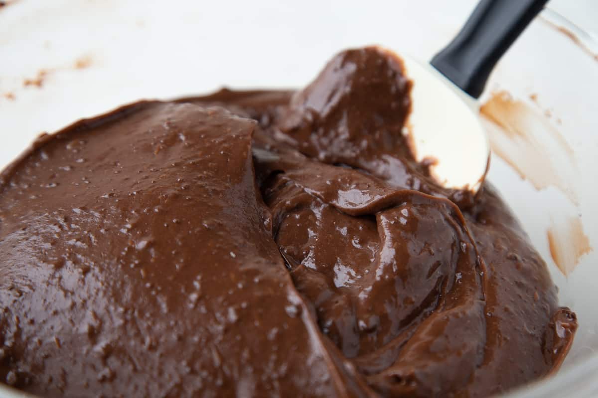 chocolate pudding in a glass bowl with a spatula.