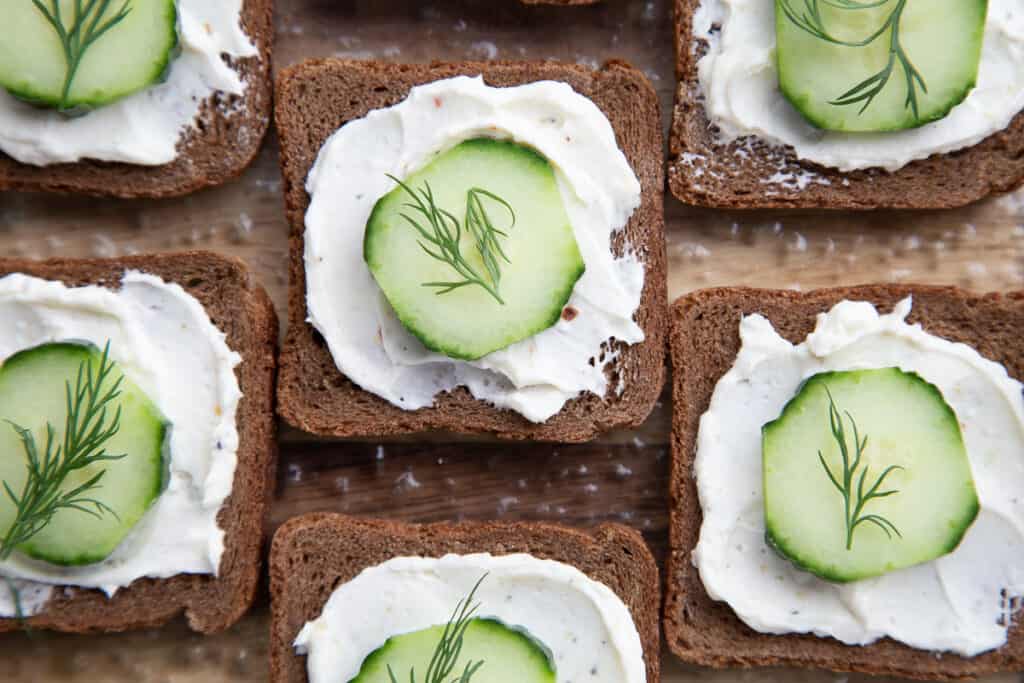 close up of open faced cucumber sandwiches on pumpernickel bread.