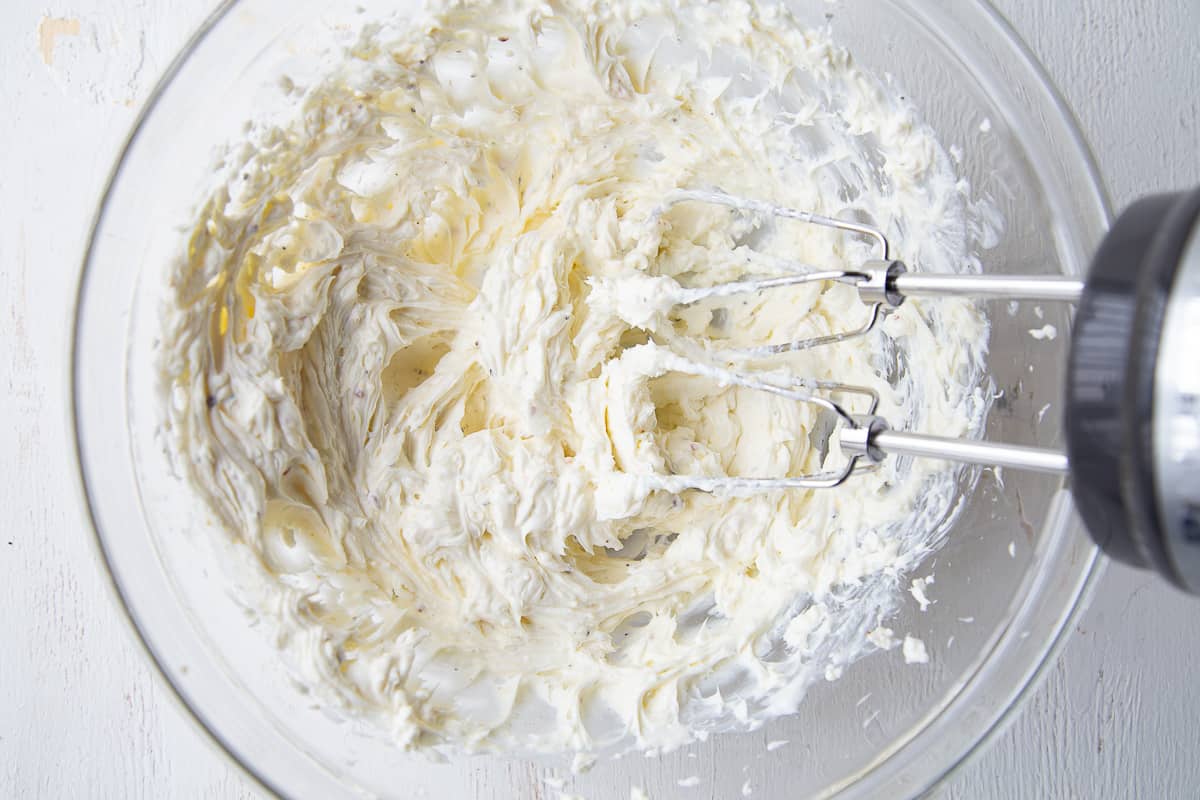 cream cheese mixture with a handheld mixer in a glass bowl.