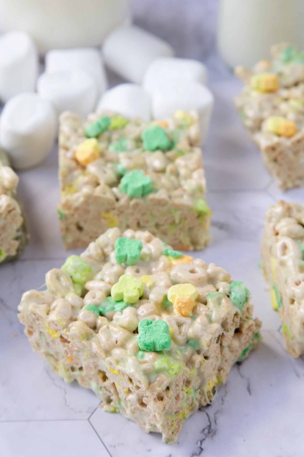 lucky charms treats on a marble table with marshmallows in the background.