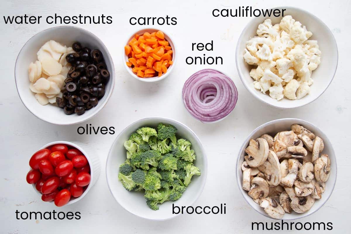 broccoli, cauliflower, tomatoes, and more chopped veggies in bowls.