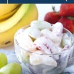 creamy fruit salad in a glass tea cup, surrounded by bananas and strawberries.