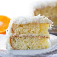slice of orange cake with coconut on a blue and white plate.